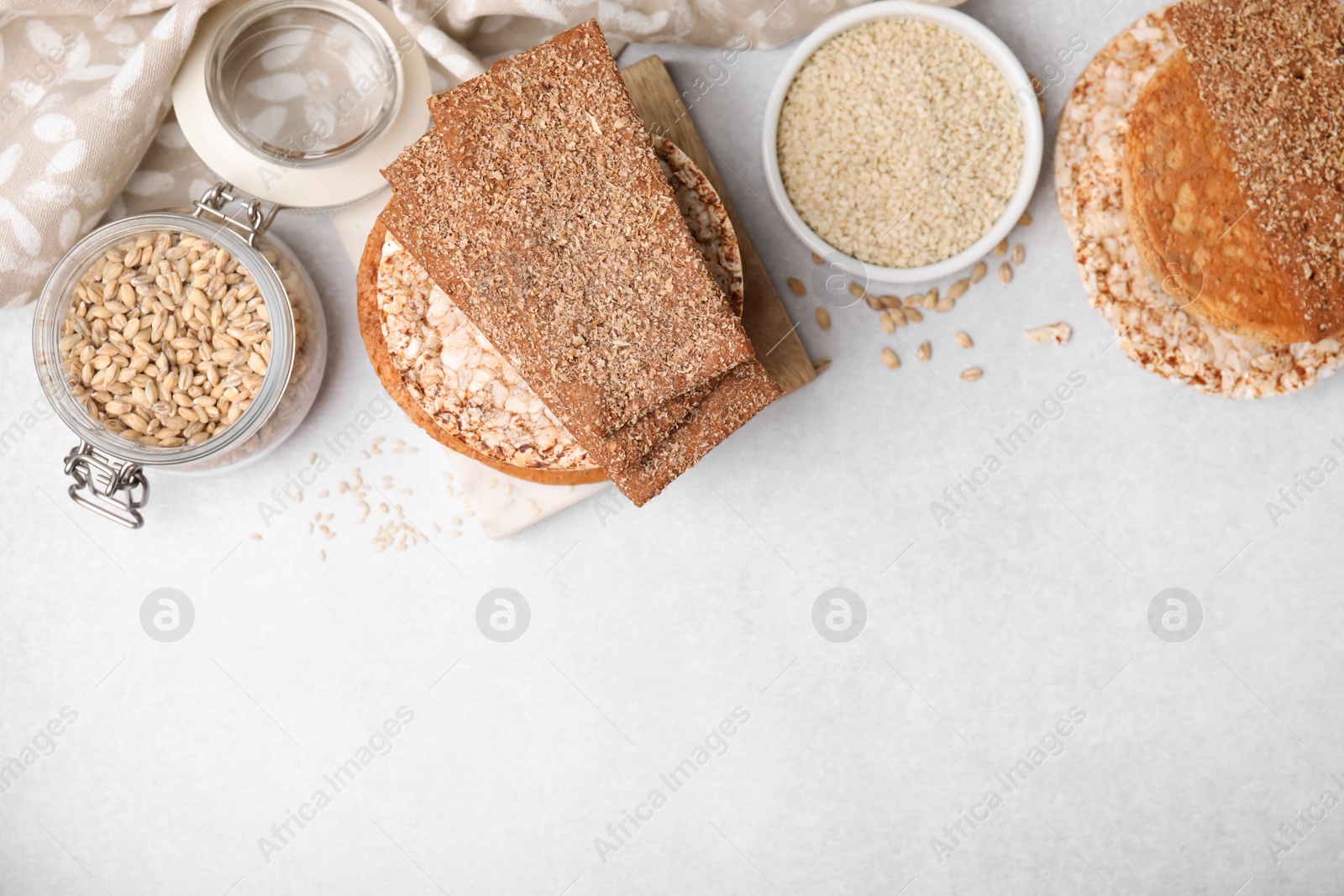 Photo of Rye crispbreads, rice cakes and rusks on white table, flat lay. Space for text