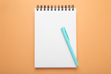 Photo of Color marker and notebook on orange background, top view