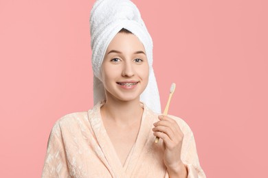 Photo of Portrait of smiling woman with dental braces and toothbrush on pink background