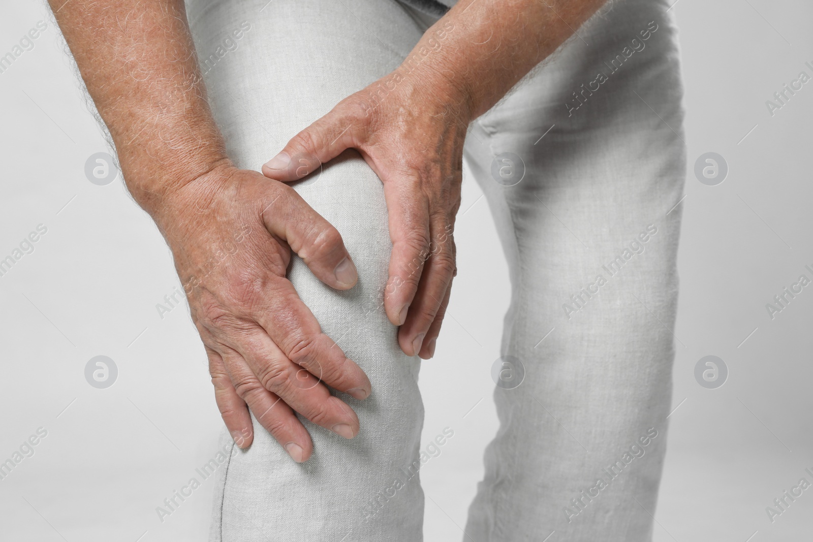 Photo of Senior man having knee problems on grey background, closeup