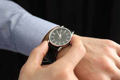 Photo of Man with luxury wrist watch on black background, closeup