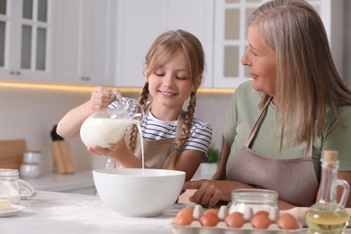 Photo of Happy grandmother with her granddaughter cooking together in kitchen