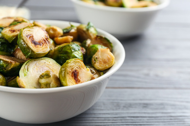 Photo of Delicious roasted brussels sprouts on grey wooden table, closeup