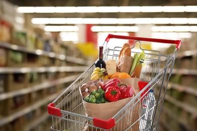 Image of Shopping cart with different groceries in supermarket