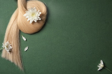 Photo of Composition with lock of blond hair and flowers on color background, top view. Space for text