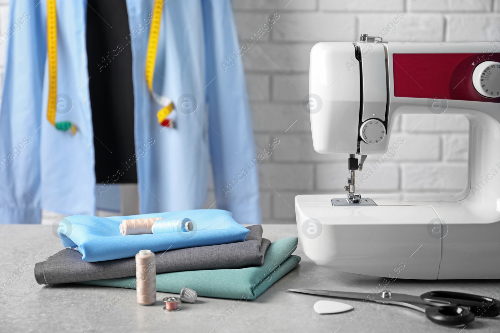 Photo of Sewing machine, fabrics and accessories for tailoring on table