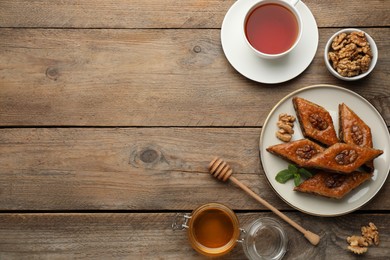 Delicious honey baklava with walnuts served on wooden table, flat lay. Space for text