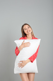 Young woman with pillow on grey background