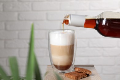 Photo of Pouring syrup into glass of tasty coffee on wooden table