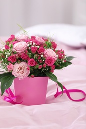 Photo of Beautiful bouquet of flowers in paper gift box on bed