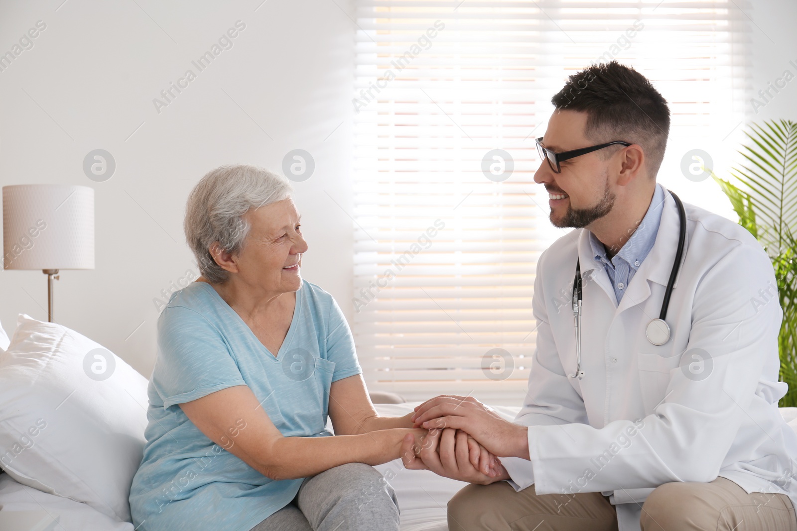 Photo of Doctor visiting senior patient in modern hospital