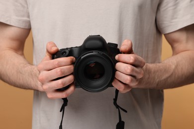 Photo of Photographer holding camera on beige background, closeup