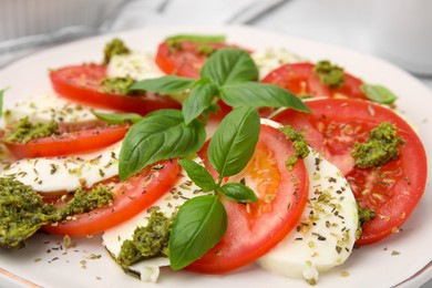 Photo of Delicious Caprese salad with pesto sauce on plate, closeup