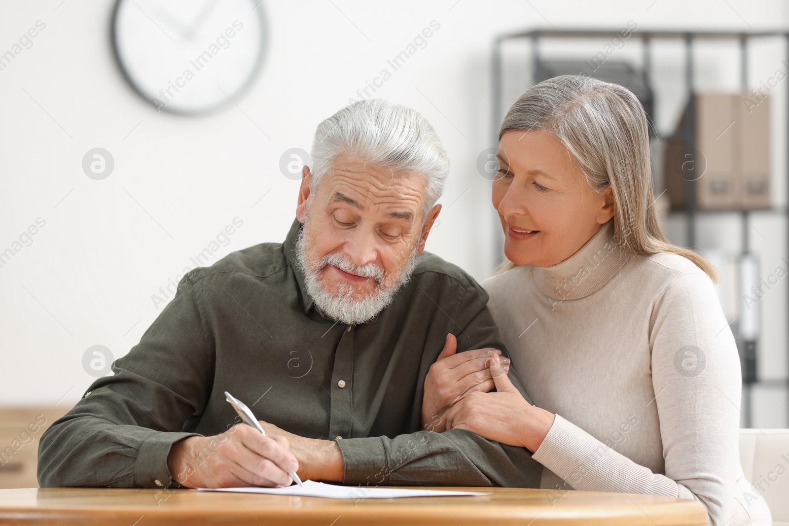 Photo of Senior couple signing Last Will and Testament indoors