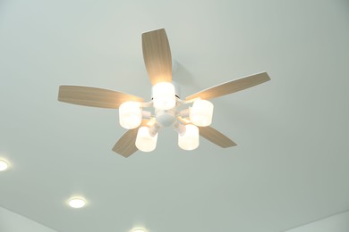 Photo of Ceiling fan with lamps indoors, low angle view