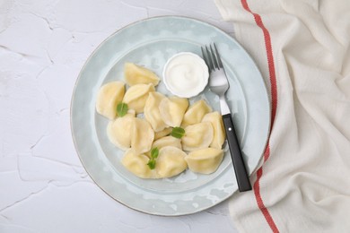 Photo of Delicious dumplings (varenyky) with cottage cheese mint and sour cream served on white table, flat lay