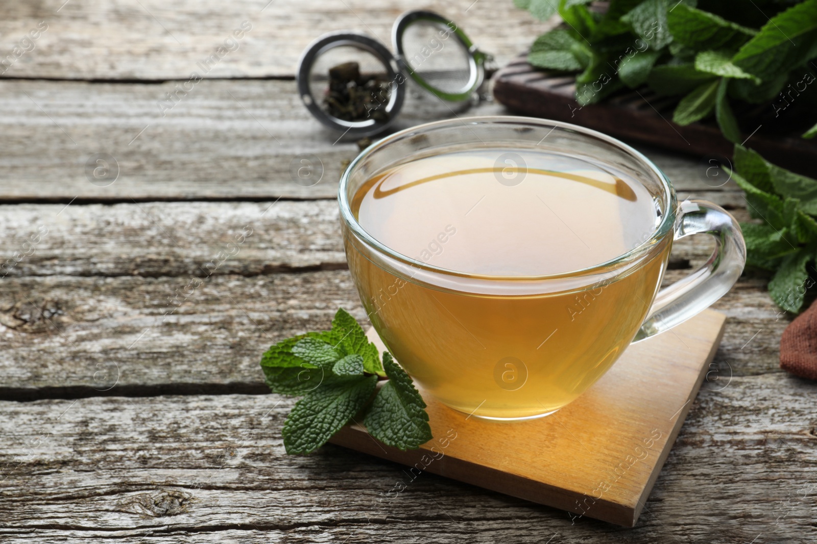 Photo of Cup of hot aromatic mint tea on wooden table. Space for text