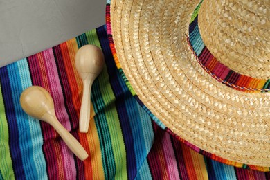 Photo of Mexican sombrero hat, maracas and poncho on table, top view