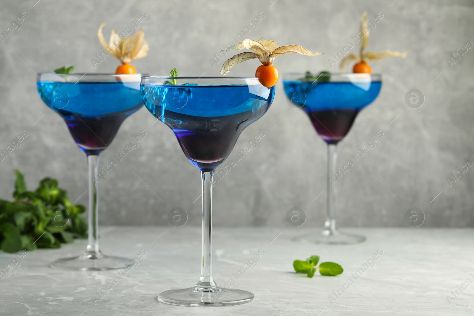 Photo of Tasty cocktail decorated with physalis fruits on grey table. Space for text