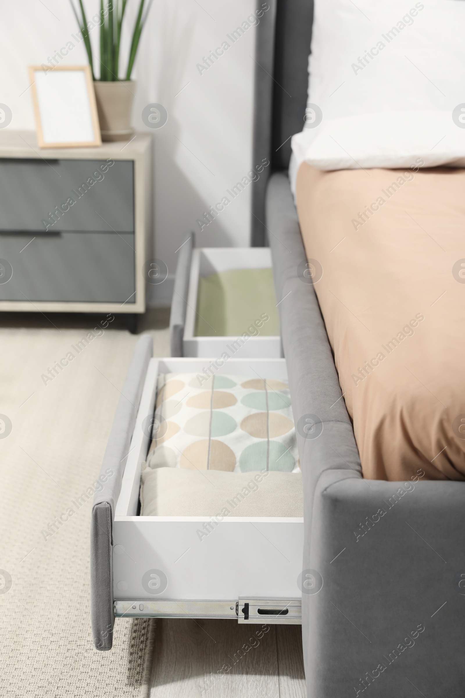 Photo of Storage drawers with bedding under modern bed in room, closeup