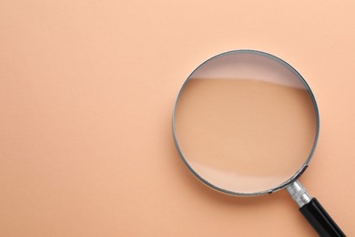 Magnifying glass on beige background, top view. Space for text