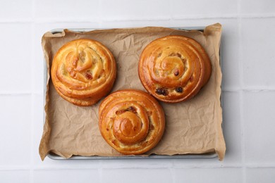 Delicious rolls with raisins on white tiled table, top view. Sweet buns