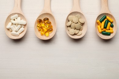 Photo of Spoons with different dietary supplements on white wooden table, flat lay. Space for text