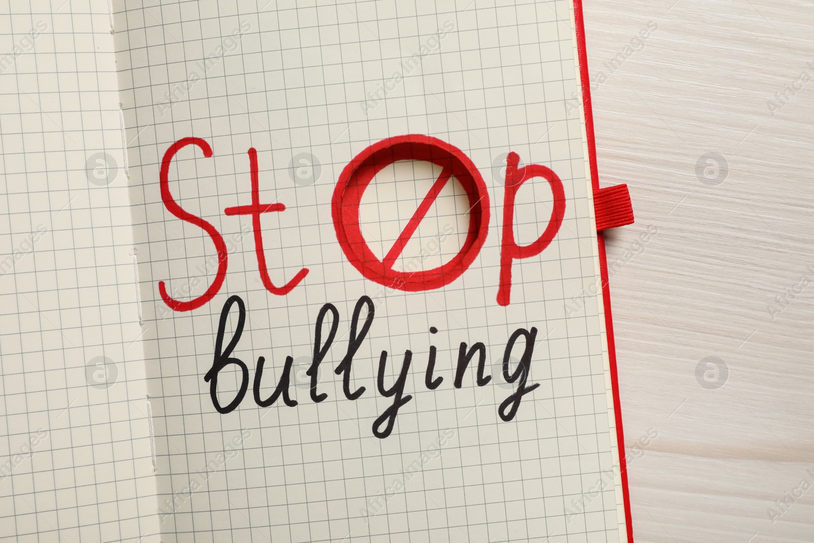 Photo of Open notebook with phrase Stop Bullying on white wooden table, top view