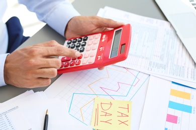 Tax accountant working with calculator at table