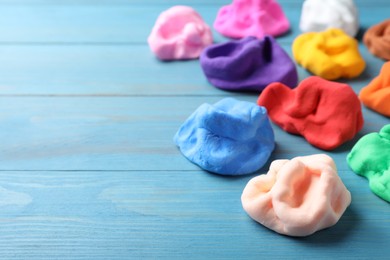 Photo of Many different colorful plasticine on light blue wooden table, closeup. Space for text