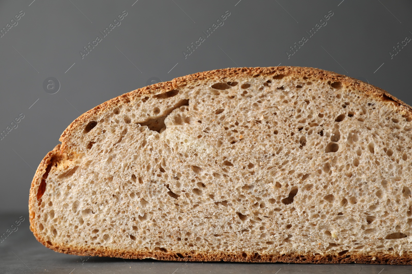 Photo of Piece of freshly baked sourdough bread on grey table, closeup