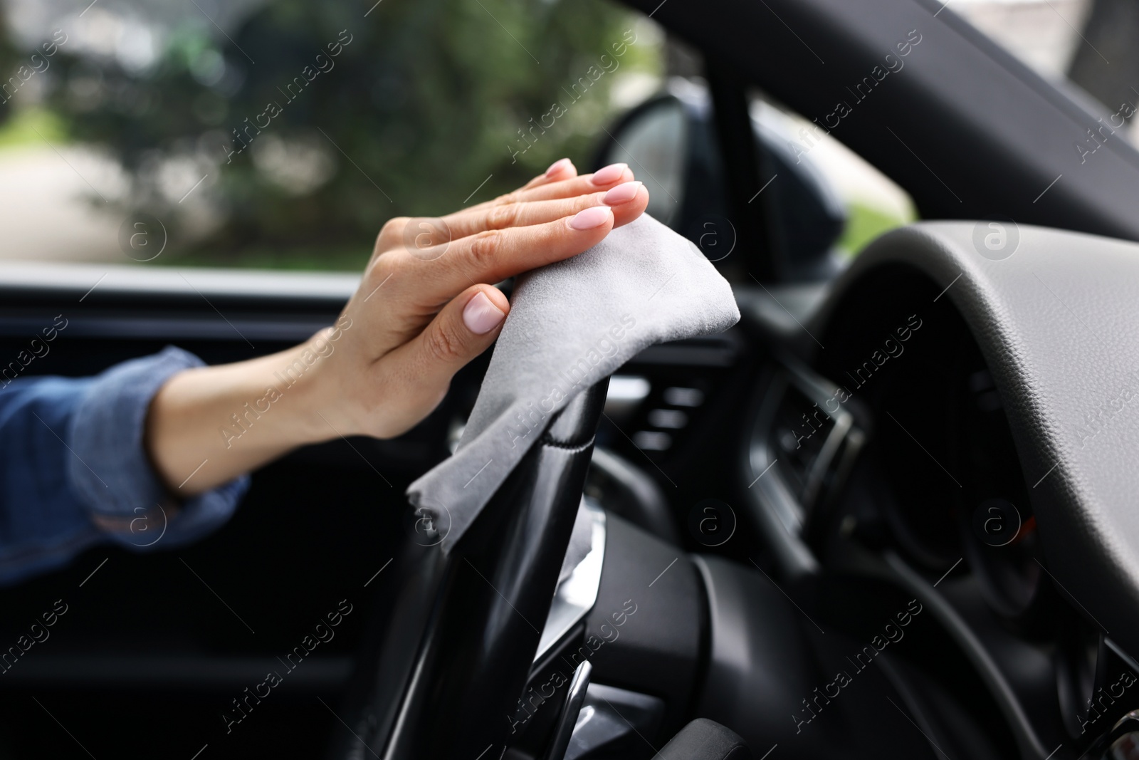 Photo of Woman wiping her modern car with rag, closeup