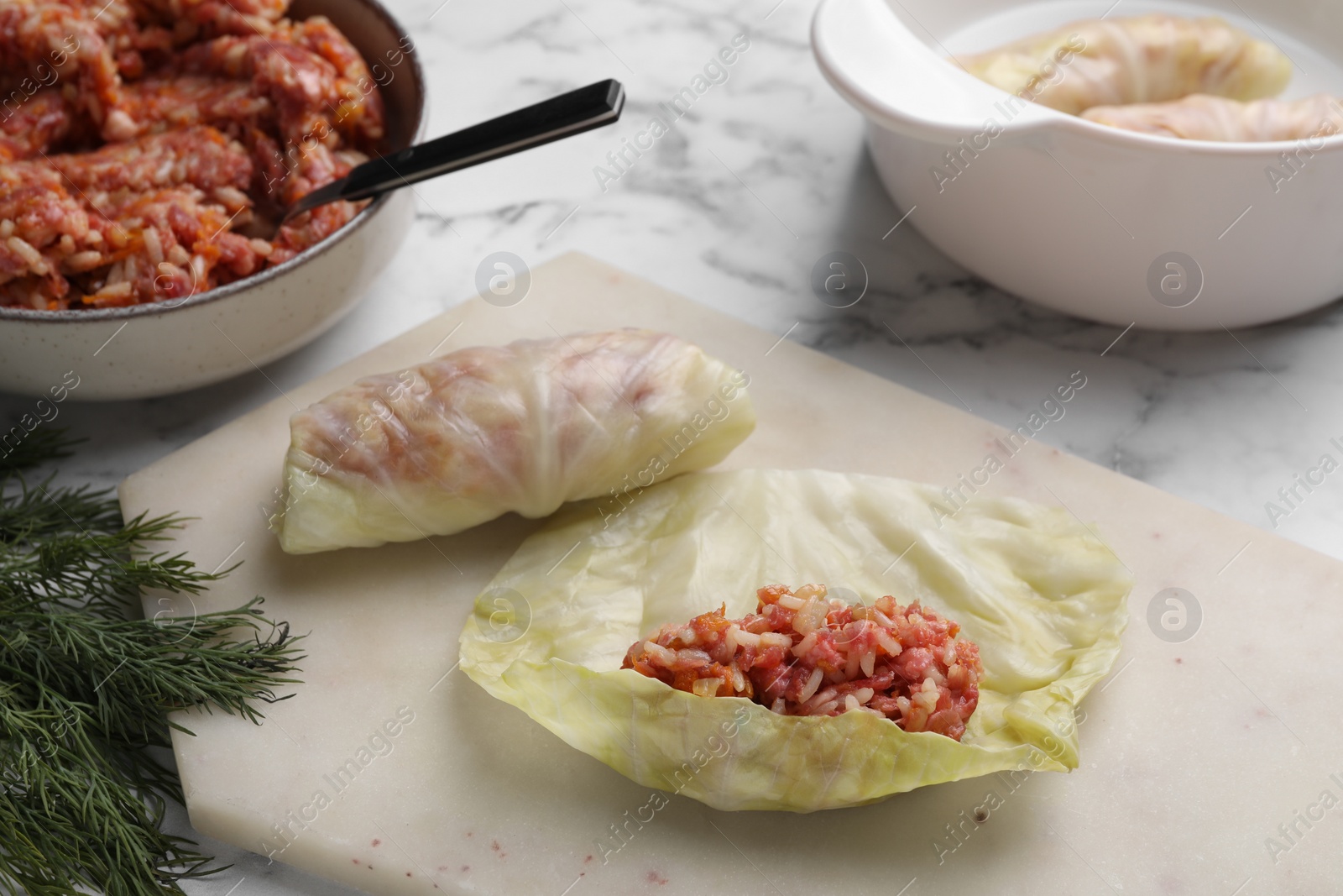 Photo of Preparing stuffed cabbage rolls on white marble table