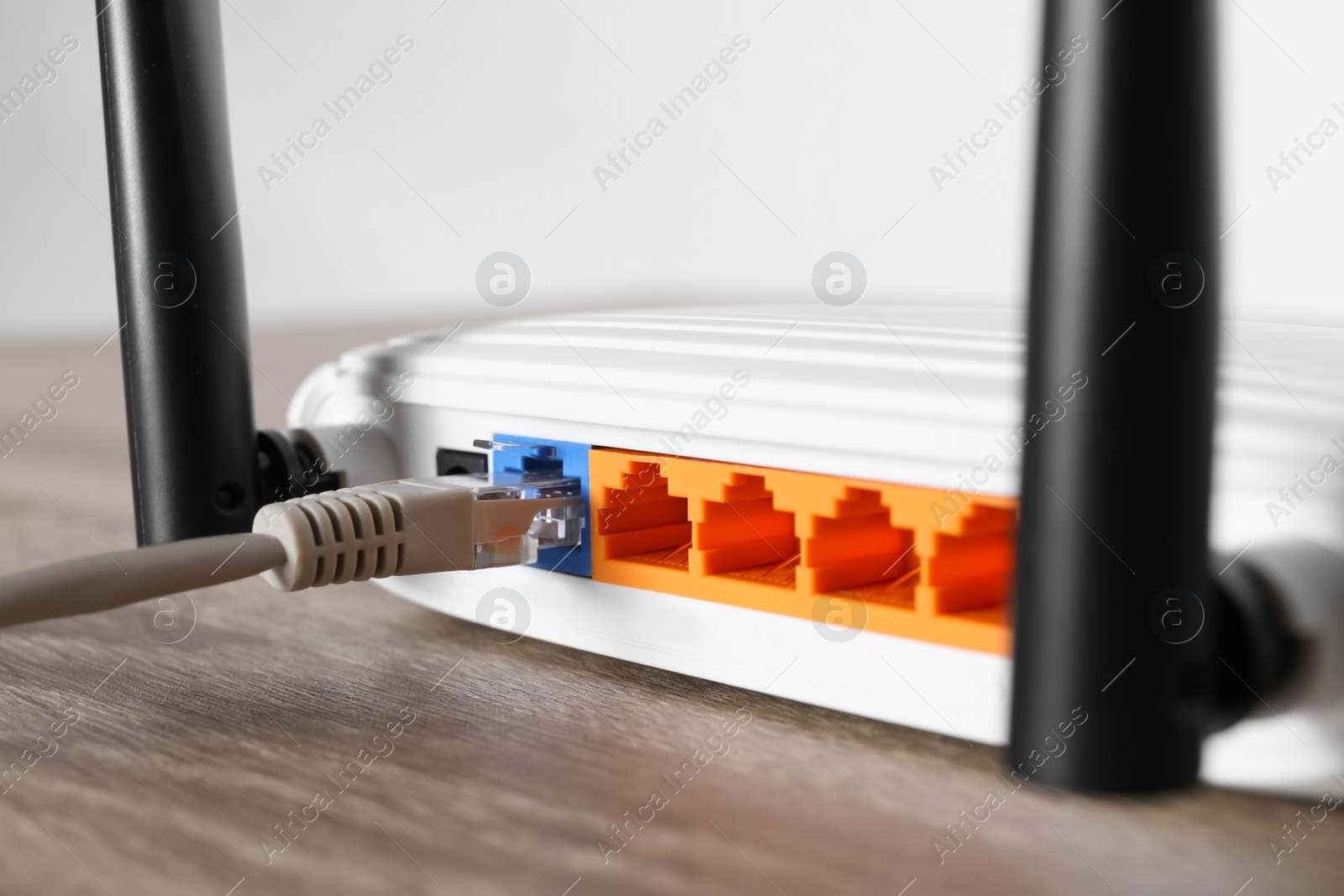 Photo of Connected cable to router on wooden table, closeup. Wireless internet communication