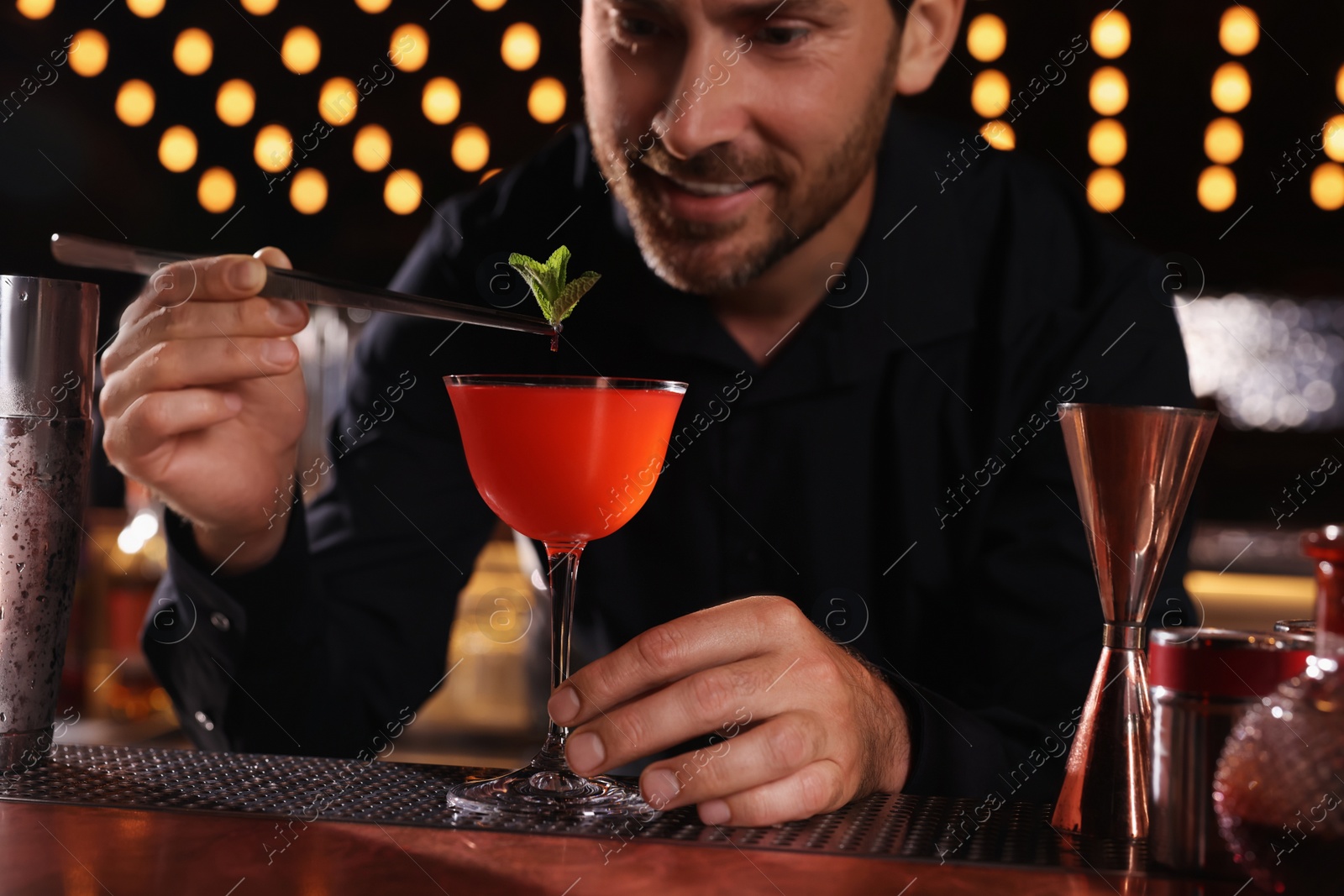 Photo of Bartender preparing fresh alcoholic cocktail in bar, selective focus