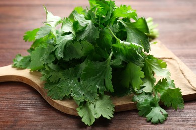 Photo of Fresh green coriander leaves on wooden table, closeup