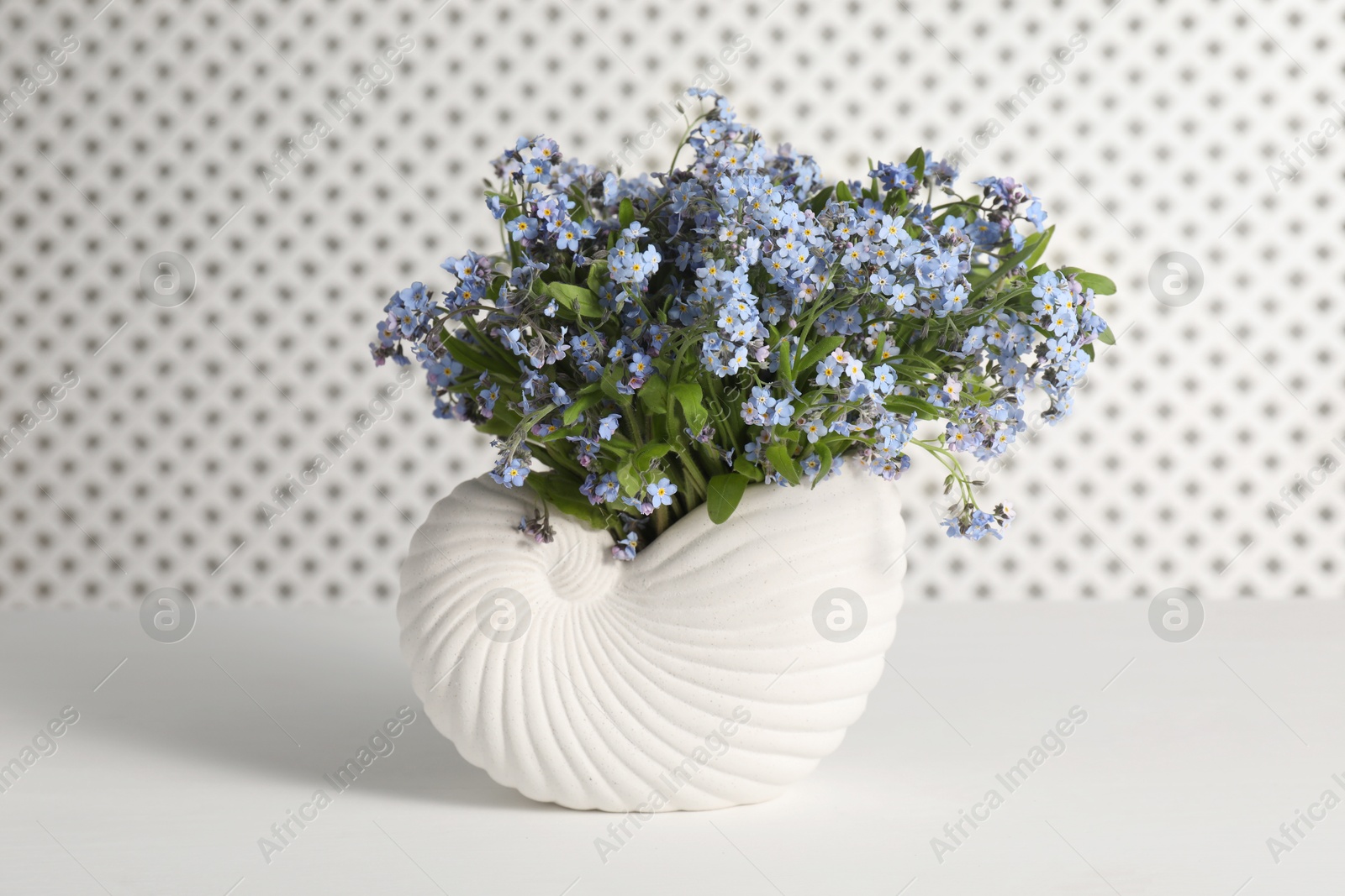 Photo of Bouquet of beautiful forget-me-not flowers in vase on white table