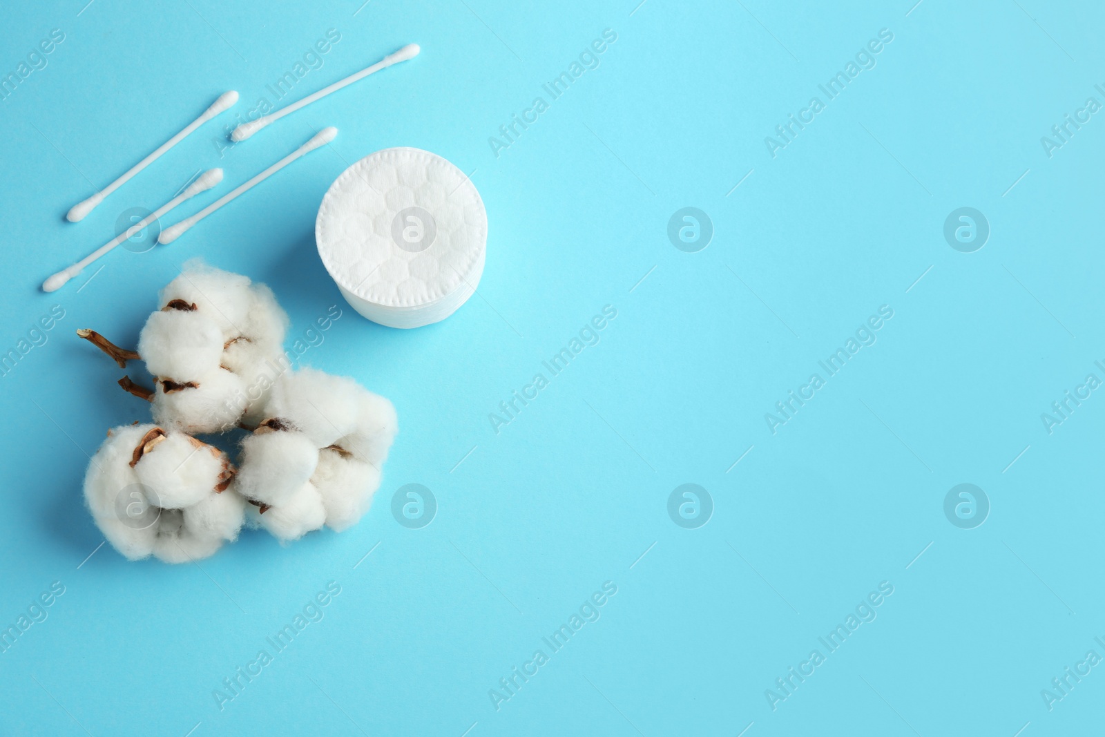 Photo of Flat lay composition with cotton pads, swabs and flowers on color background. Space for text