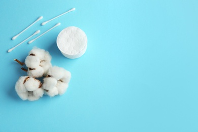 Photo of Flat lay composition with cotton pads, swabs and flowers on color background. Space for text