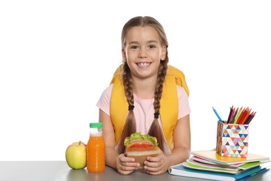 Photo of Schoolgirl with healthy food and backpack sitting at table on white background