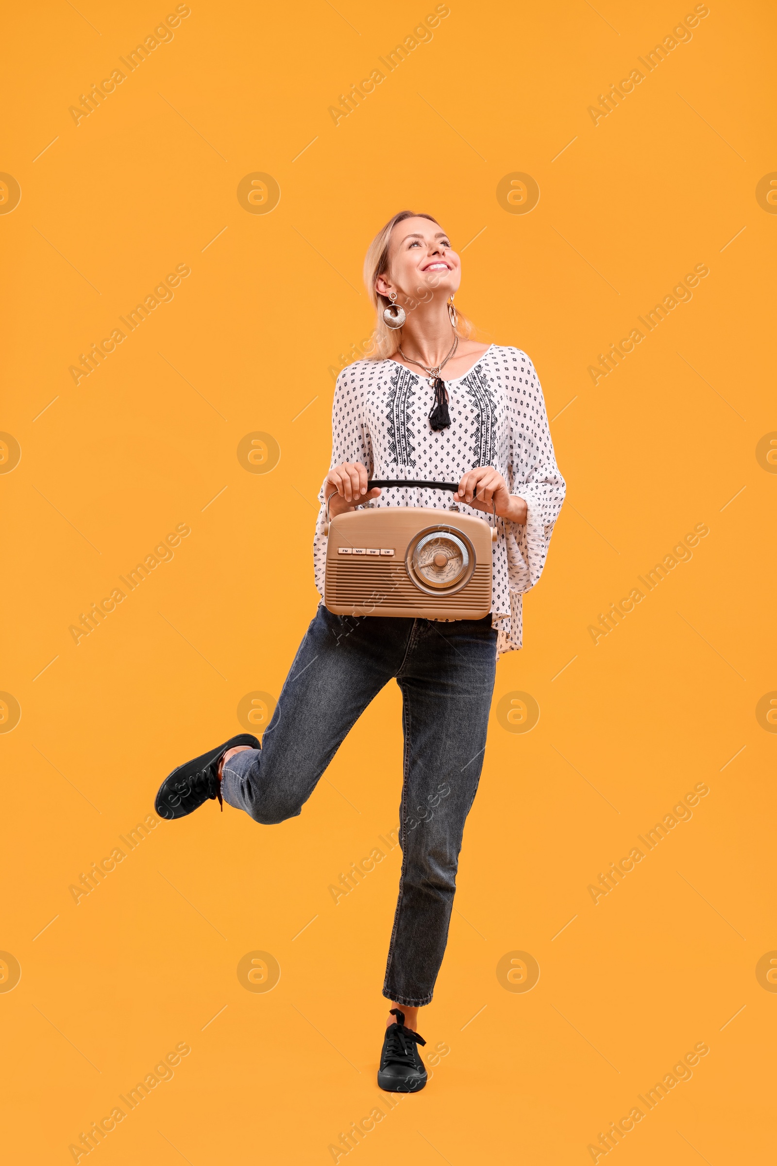 Photo of Portrait of happy hippie woman with retro radio receiver on yellow background