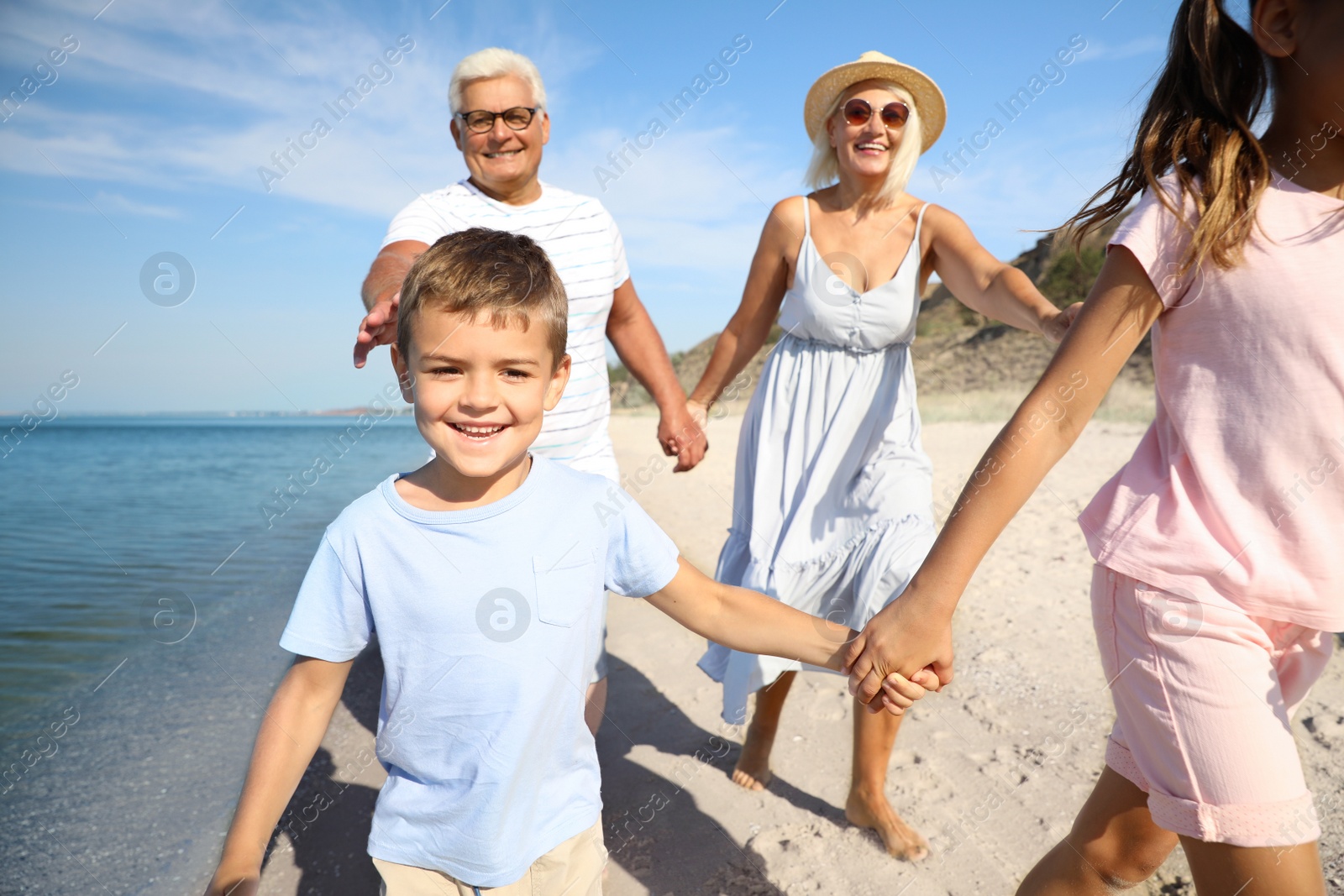 Photo of Cute little children with grandparents spending time together on sea beach