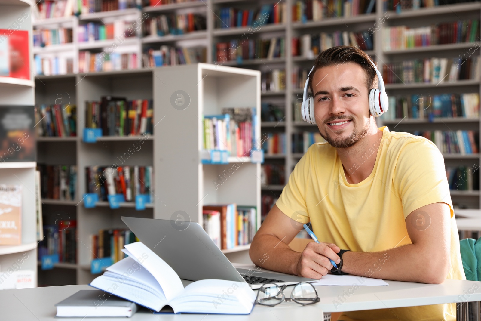 Photo of Young man studying at table in modern library