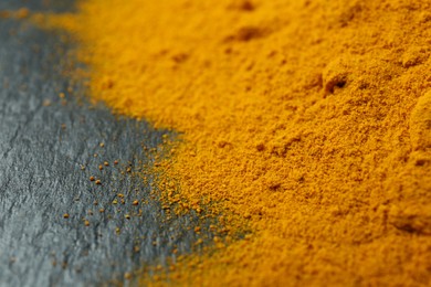 Turmeric powder on black textured table, closeup