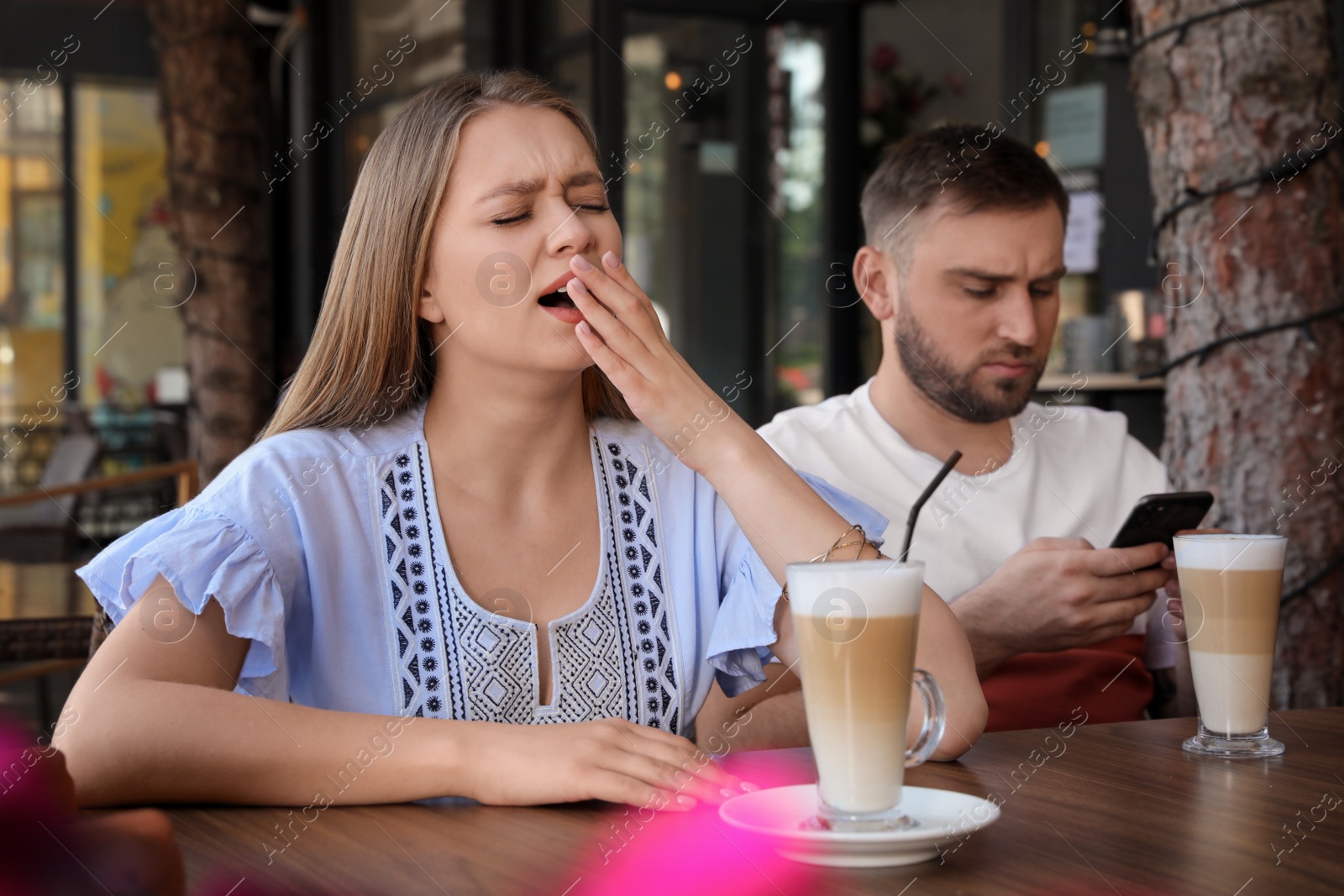 Photo of Young woman having boring date with guy in outdoor cafe