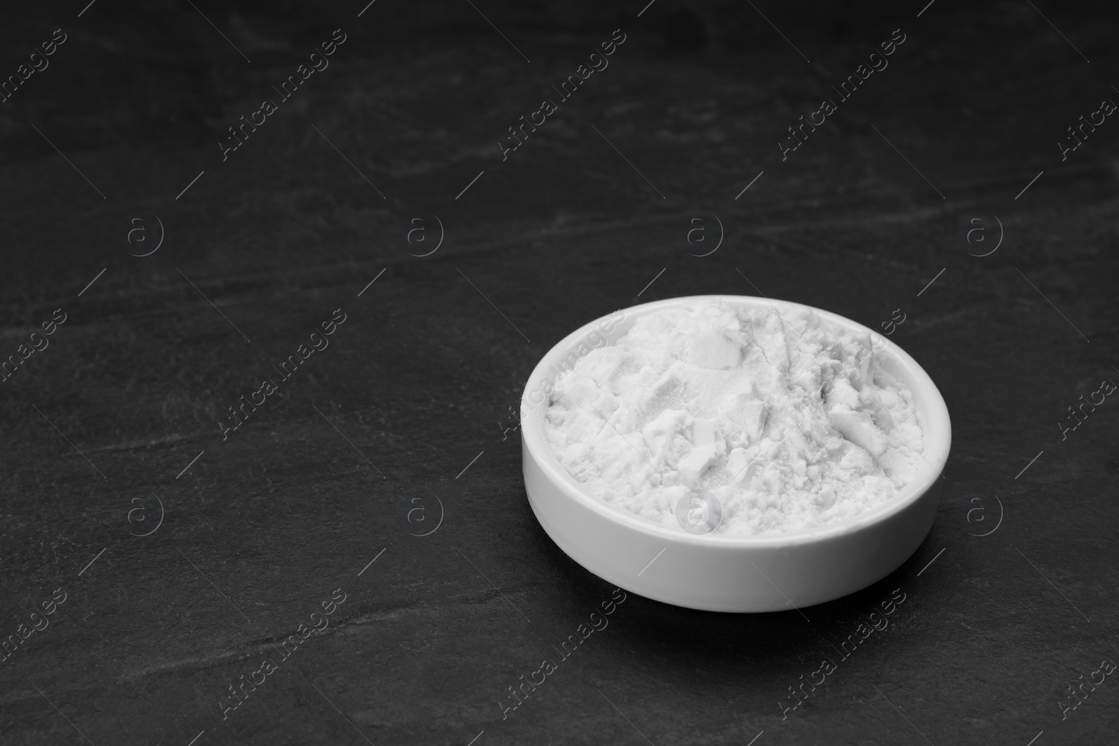 Photo of Bowl of natural starch on black table, space for text