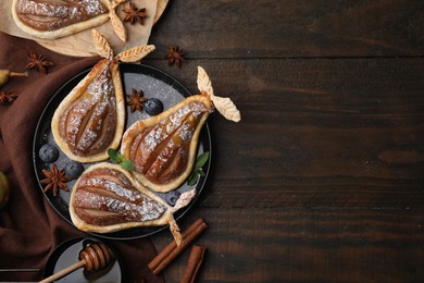 Photo of Delicious pears baked in puff pastry with powdered sugar served on wooden table, flat lay. Space for text