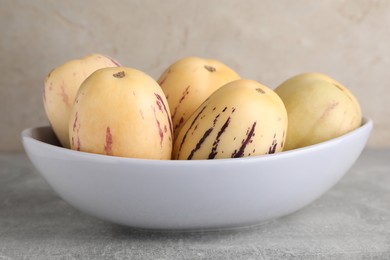 Photo of Fresh ripe pepino melons in bowl on grey table