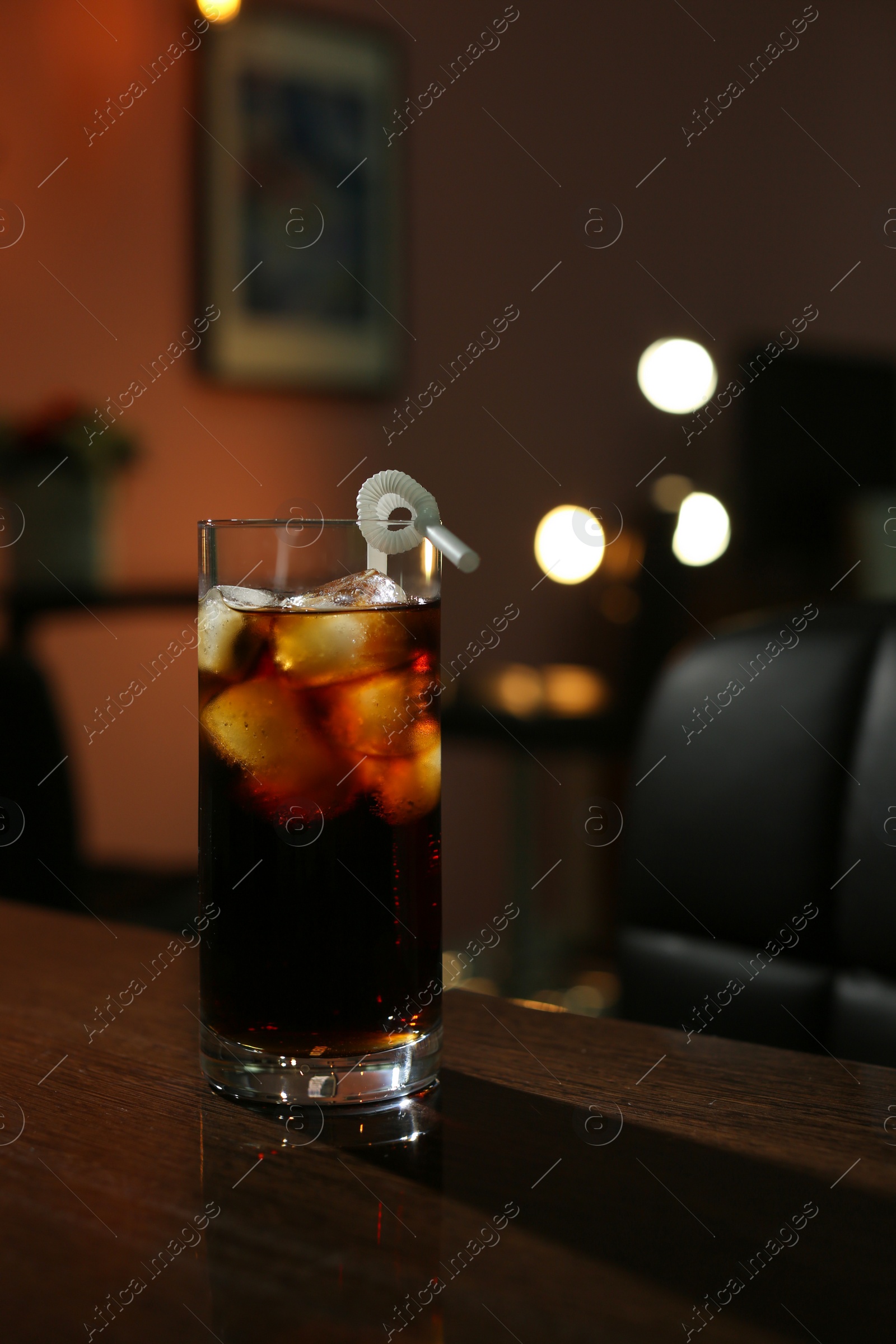 Photo of Glass of cold cola on table in dark room. Space for text