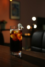 Photo of Glass of cold cola on table in dark room. Space for text